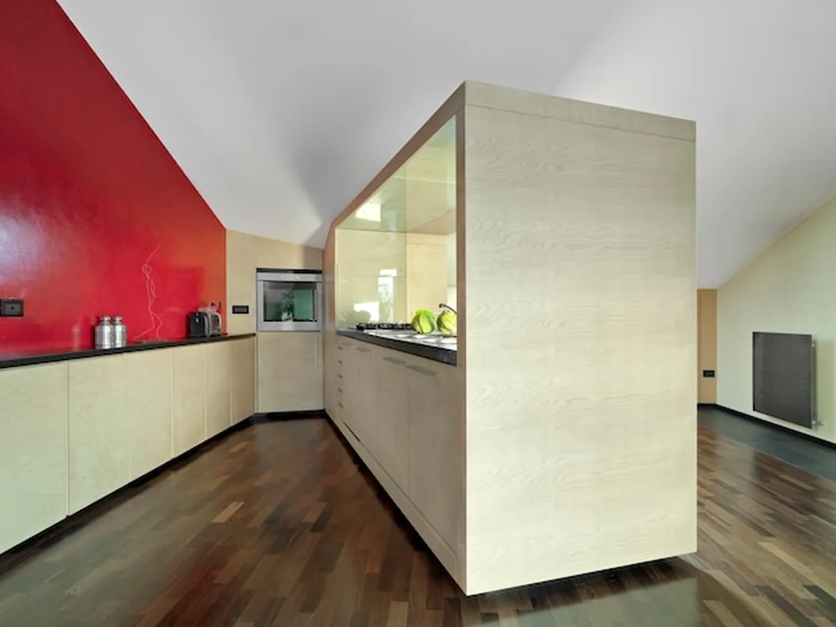 Nowoczesna kuchnia na poddaszu z drewnianą podłogą i czerwonymi ścianami