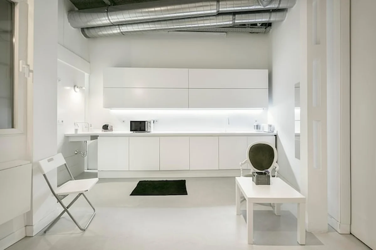 Biała kuchnia i jadalnia w industrialnym mieszkaniu w centrum europejskiego miasta