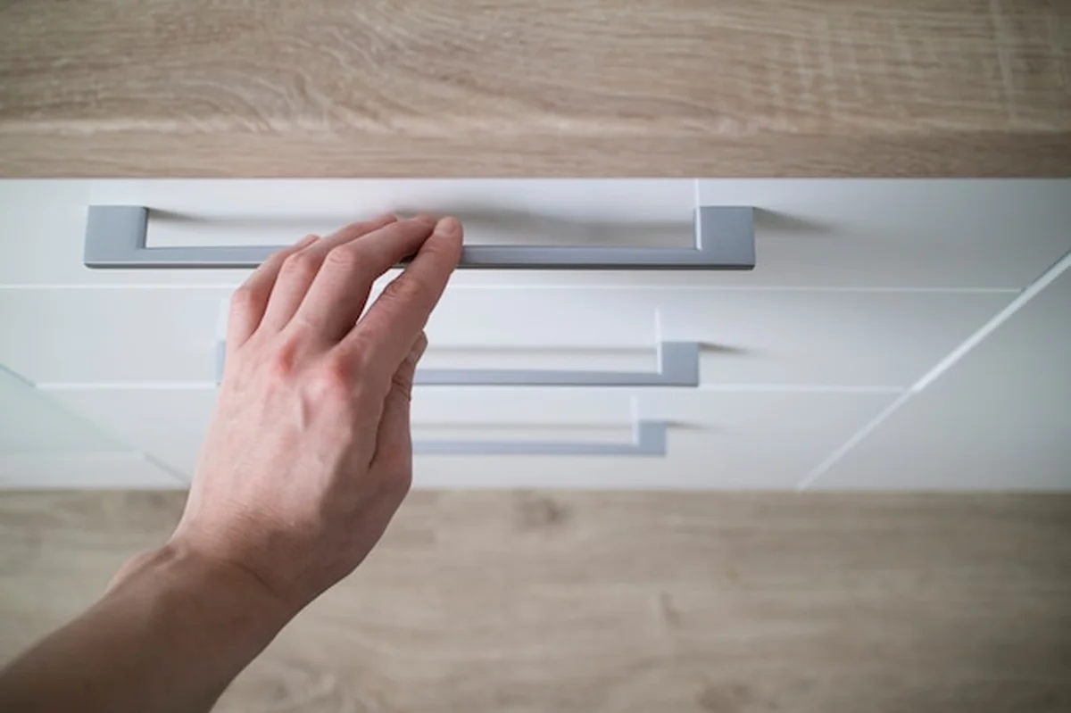 Ręka mężczyzny w białej szafce kuchennej z szufladą