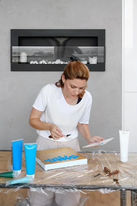 Kobieta malująca obraz farbami akrylowymi w domu