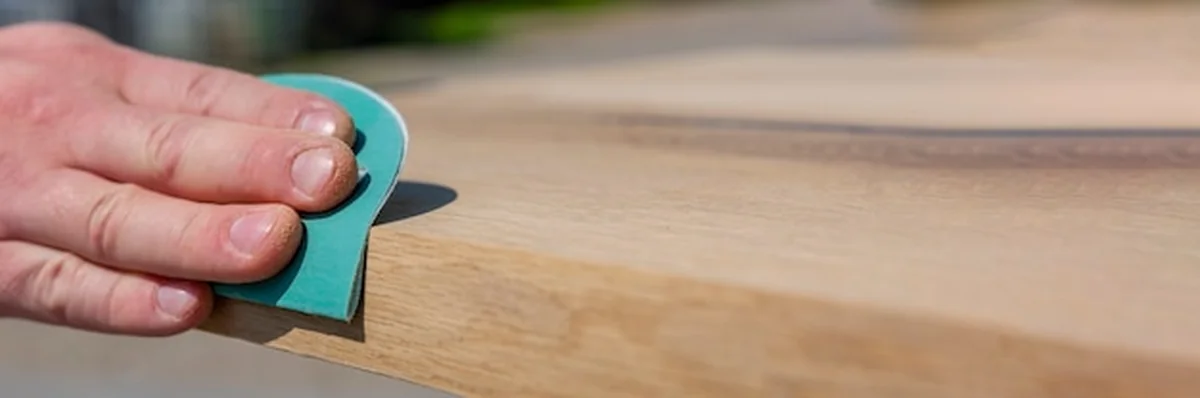 Stolarz szlifuje drewnianą deskę papierem ściernym