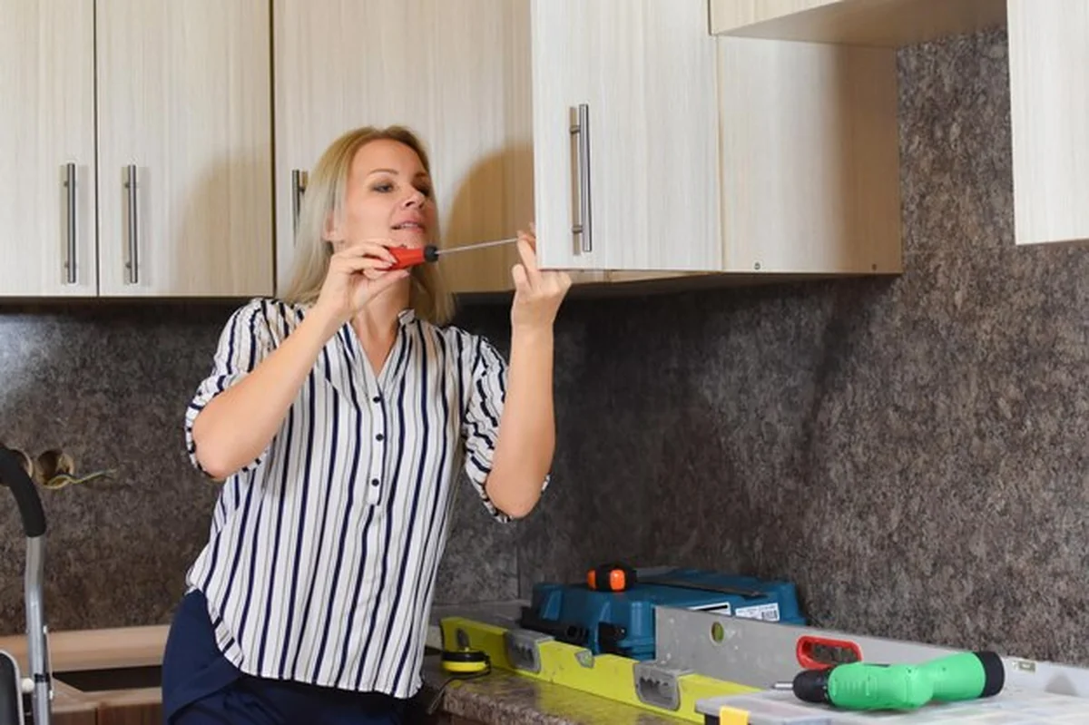 Kobieta naprawia meble w kuchni