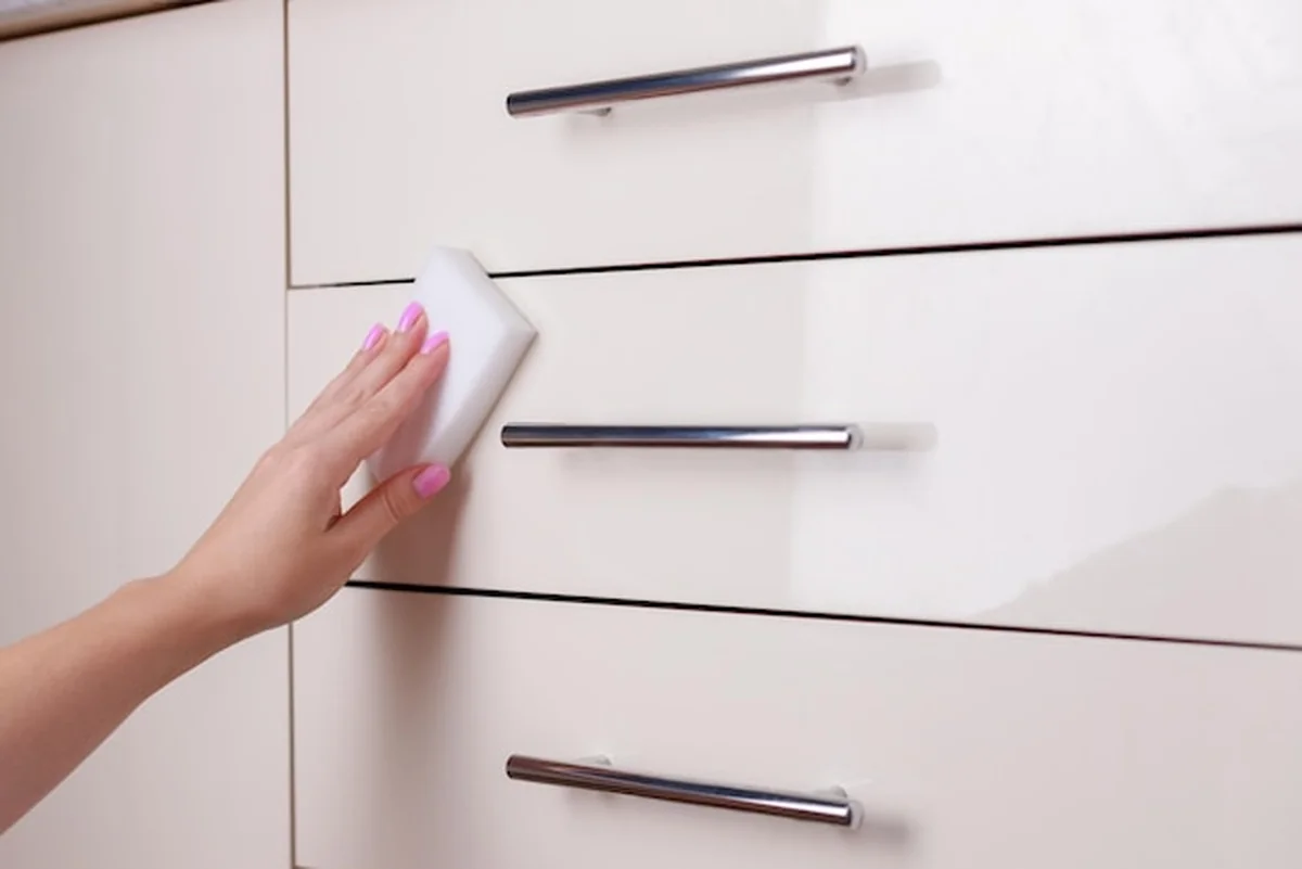 Kobieta pocierająca meble kuchenne gąbką z bliska