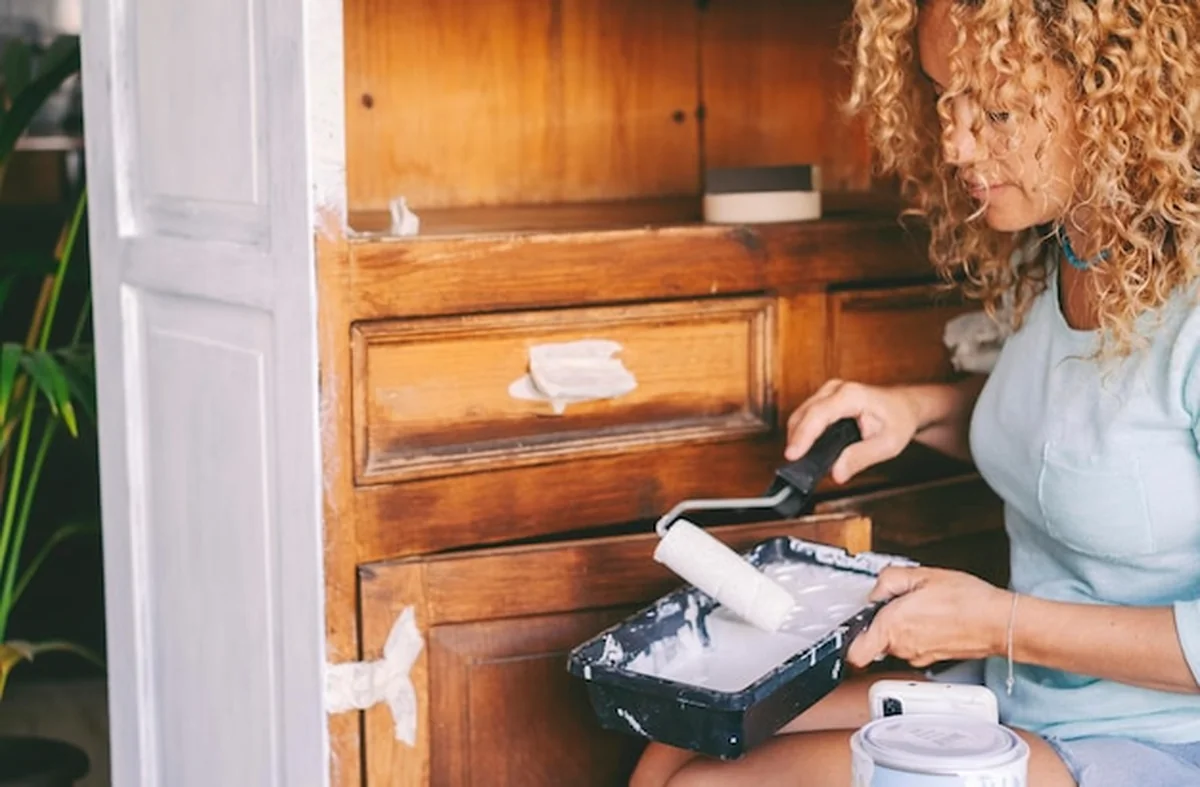 Kobieta odnawia stare drewniane meble kuchenne na biało w domu