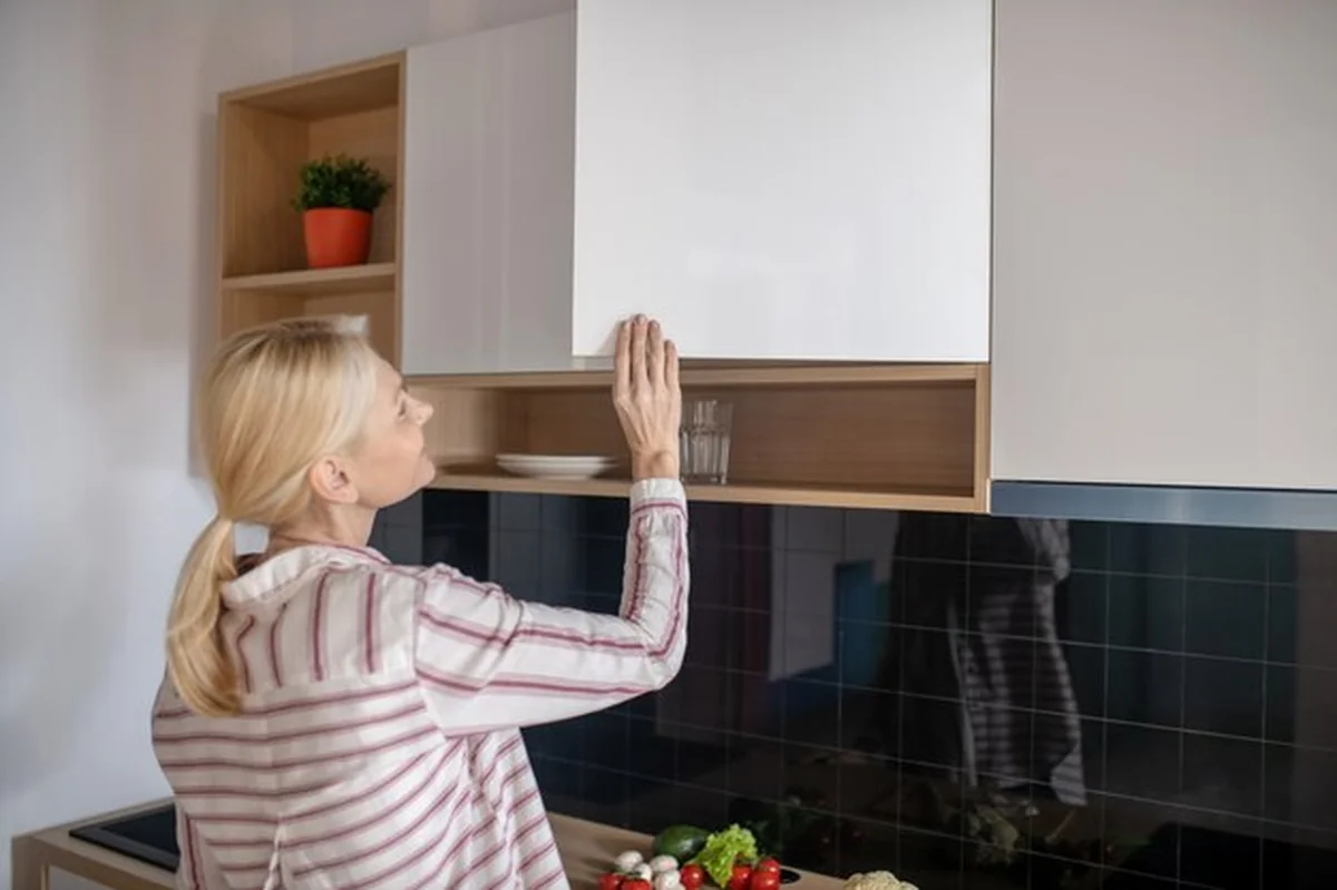 Blondynka kobieta otwiera szafkę w kuchni