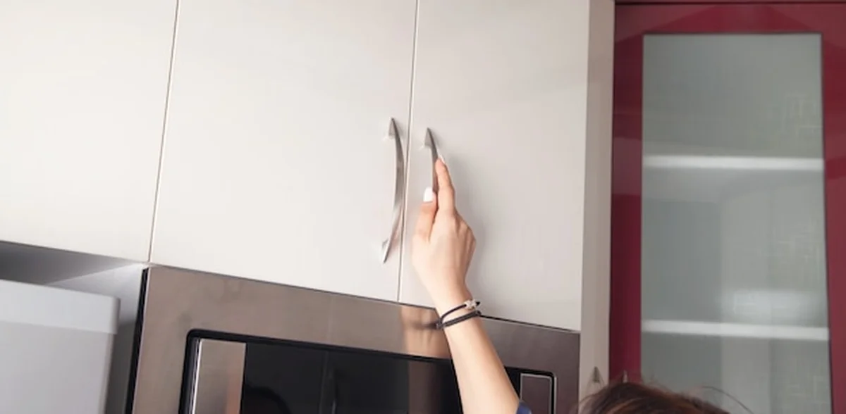 Kaukaska kobieta otwiera drzwi mebli kuchennych