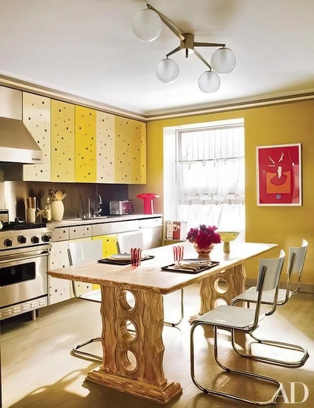 Kuchnia z żółtymi szafkami i czerwonym obrazem na ścianie